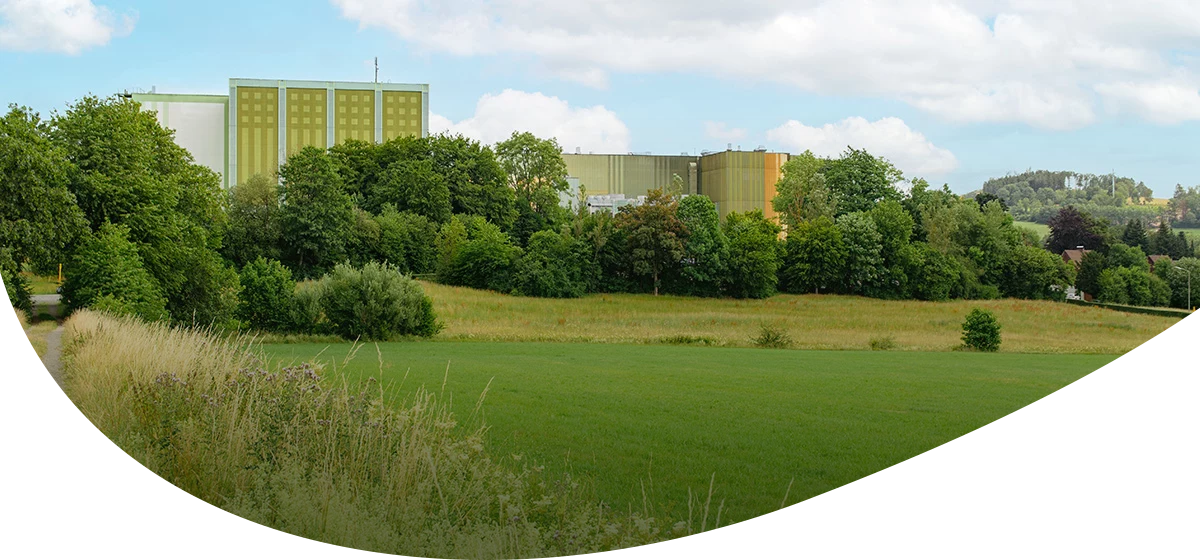 Grünes Krombacher Brauerei Gebäude von außen, davor eine Wiese mit Bäumen.