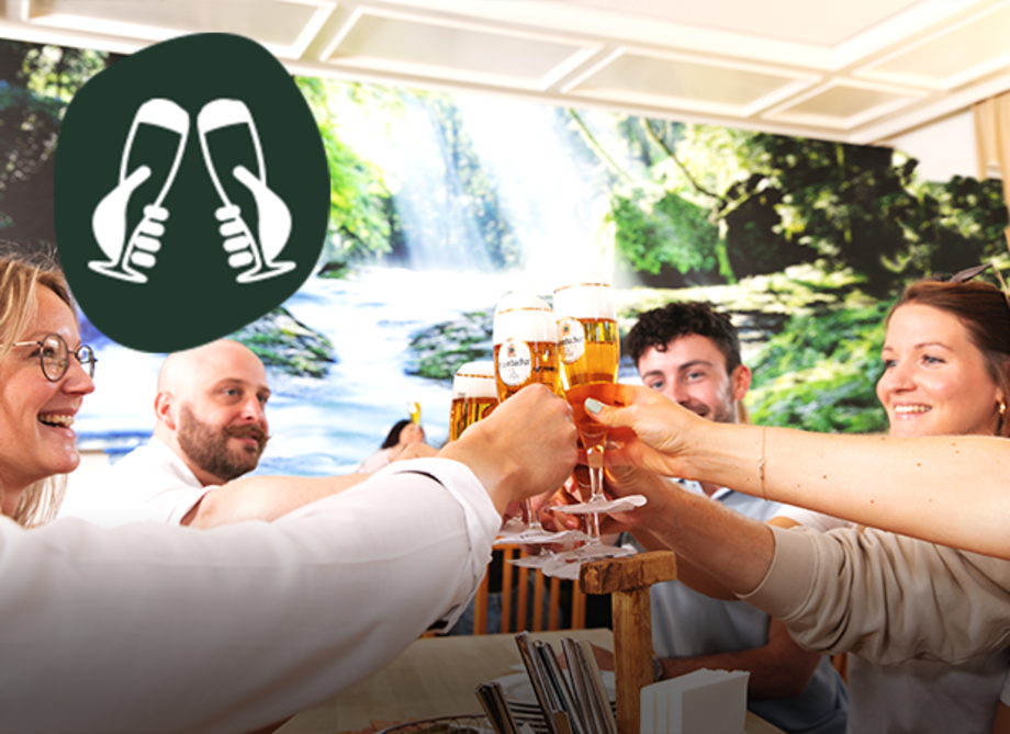 Mehrere Personen sitzen in der Krombacher Braustube und stoßen mit Biergläsern an.