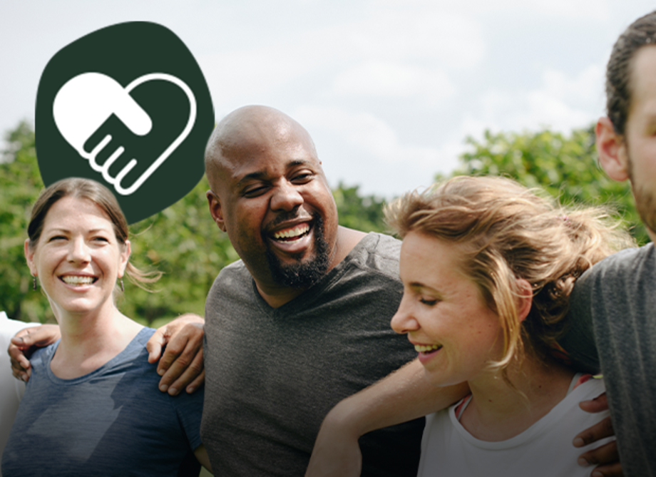 Vier Menschen stehen aneinandergereiht nebeneinander und legen sich die Arme über die Schultern, alle lächeln. 