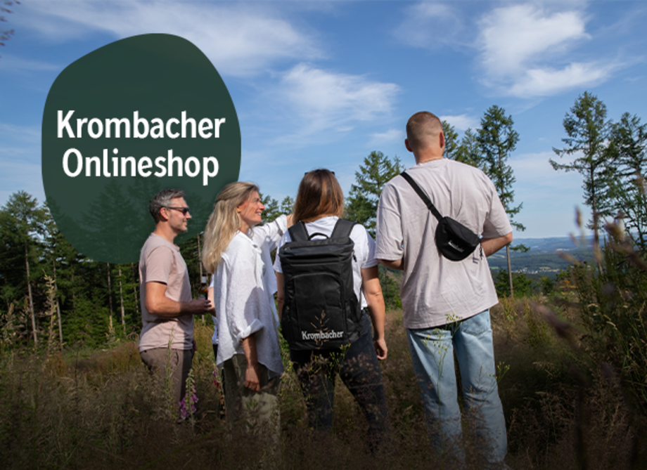 Gruppe von vier Personen auf einer Lichtung im Wald in sommerlicher Kleidung mit Krombacher Rucksack. Text in Sprechblase: 'Krombacher Onlineshop'.