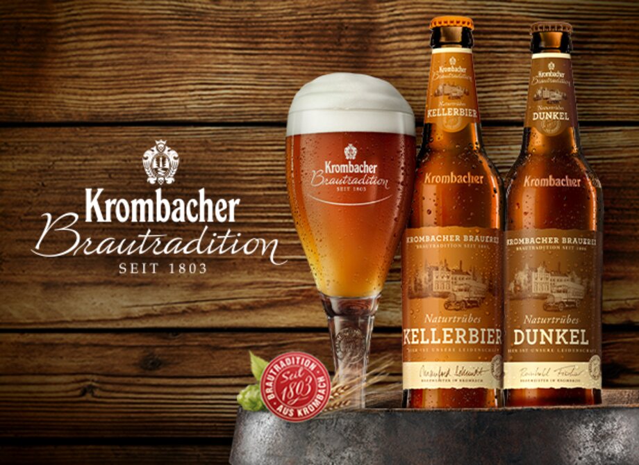 Zwei Krombacher Bierflaschen, eine Kellerbier und eine Dunkel, stehen neben einem Glas mit dunklem Bier. Im Hintergrund ist das Logo Krombacher Brautradition seit 1803 sichtbar.