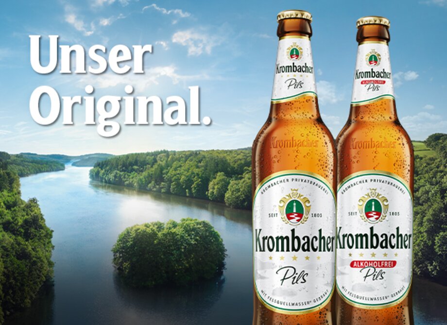 Zwei Flaschen Krombacher Pils stehen vor der Krombacher Insel. Der Text Unser Original ist sichtbar.