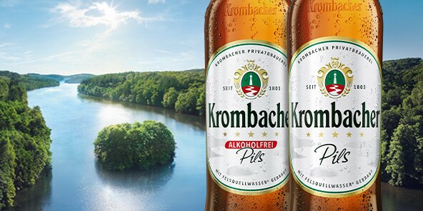 Zwei Flaschen Krombacher Pils und Krombacher Alkoholfrei stehen vor der Krombacher Insel.