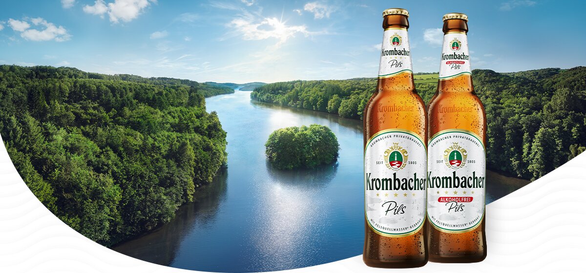 Zwei Flaschen Krombacher Pils stehen vor der Krombacher Insel. 