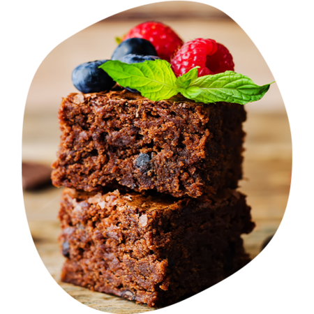 Zwei übereinander gestapelte quadratische Schokoladenbrownies mit Blaubeeren, Himbeeren und Minzblatt als Dekoration.