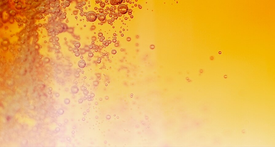 Aufsteigende Bläschen in goldener Flüssigkeit – Symbol für die Gärung mit Hefe.