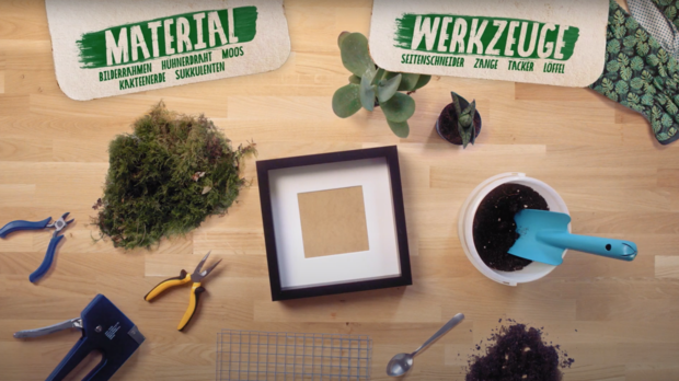 Auf einem Tisch liegen verschiedene Materialien und Werkzeuge für ein Bastelprojekt. Oben links steht 'MATERIAL', oben rechts 'WERKZEUGE', darunter sind eine Schaufel, Zange, Schere und ein Bilderrahmen zu sehen.