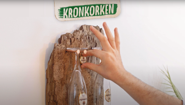 Gläser hängen zwischen den Nägeln und Kronkorken sind an das Holz angebracht.