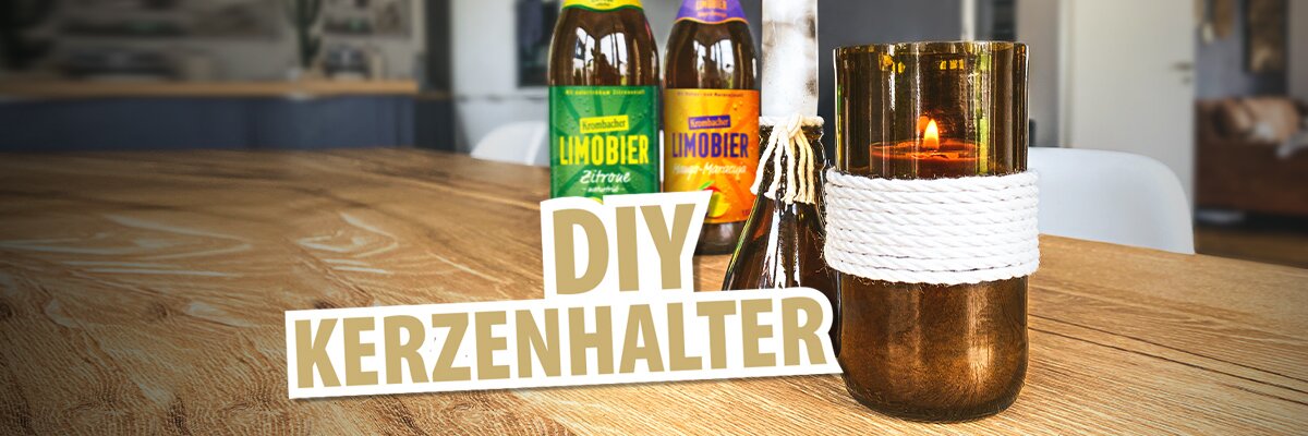 Zwei Flaschen 'Limobier' in den Geschmacksrichtungen Zitrone und Holunderblüte stehen hinter einem DIY-Kerzenhalter aus Glas mit einer Kerze. Der Text 'DIY KERZENHALTER' ist in großen, hellen Buchstaben im Vordergrund.
