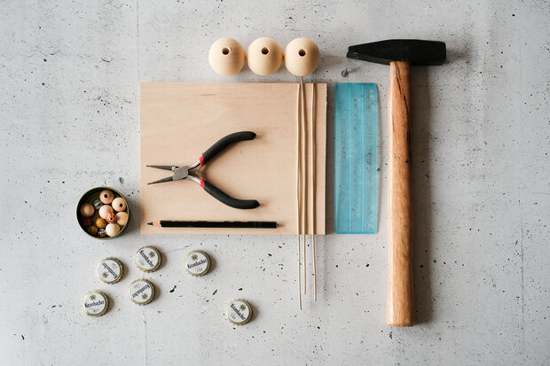 Auf einem Tisch verschiedene Basteluntensilien wie Schere, Kronkorken, Holzkugeln u.s.w..