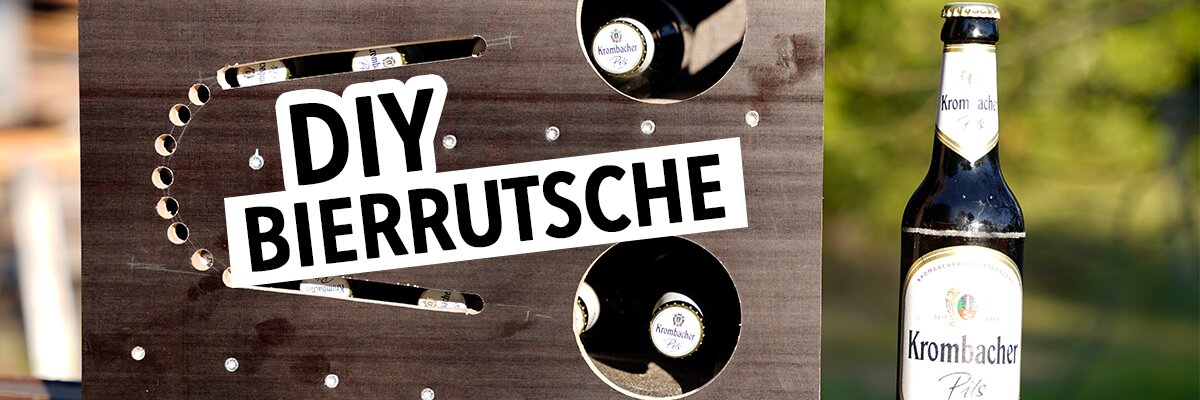 Ein schwarzes Holzgestell mit zwei runden Ausschnitten, in denen Flaschen stehen. Daneben eine Bierflasche von 'Krombacher'. Der Text 'DIY BIERRUTSCHE' ist in großen, weißen Buchstaben auf schwarzem Hintergrund zu sehen.