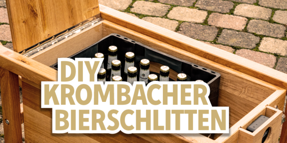 Ein Holzstuhl mit einem offenen Fach, das eine Kiste mit Flaschen enthält. Darauf steht der Text 'DIY Krombacher Bierschlitten'.