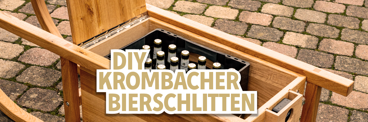 Ein Holzstuhl mit einem offenen Fach, das eine Kiste mit Flaschen enthält. Darauf steht der Text 'DIY Krombacher Bierschlitten'.