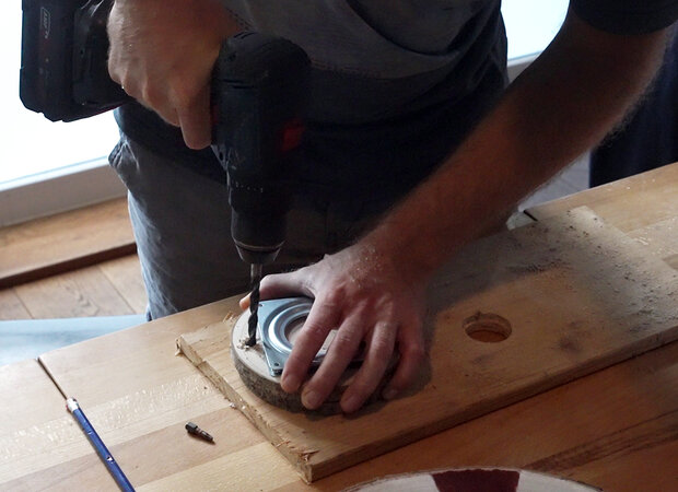 Löcher werden in eine kleine Holzscheibe gebohrt.