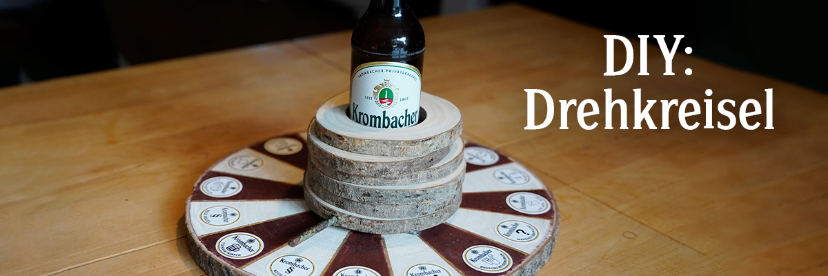 Holzscheiben mit einer Krombacher Pils Flasche und Text: DIY Drehkreisel.
