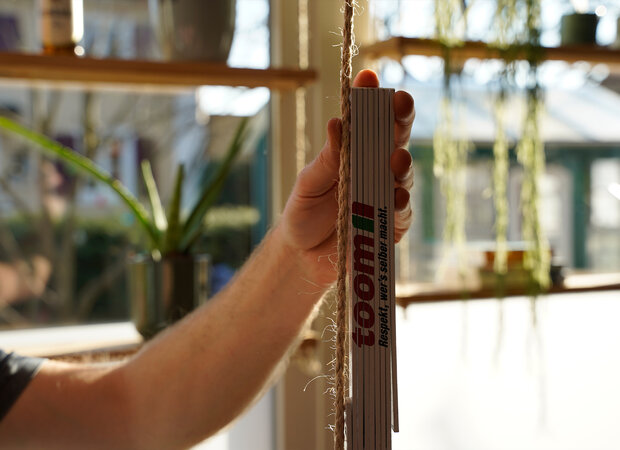 Zollstock wird an eine senkrecht gehaltene Schnur gehangen.