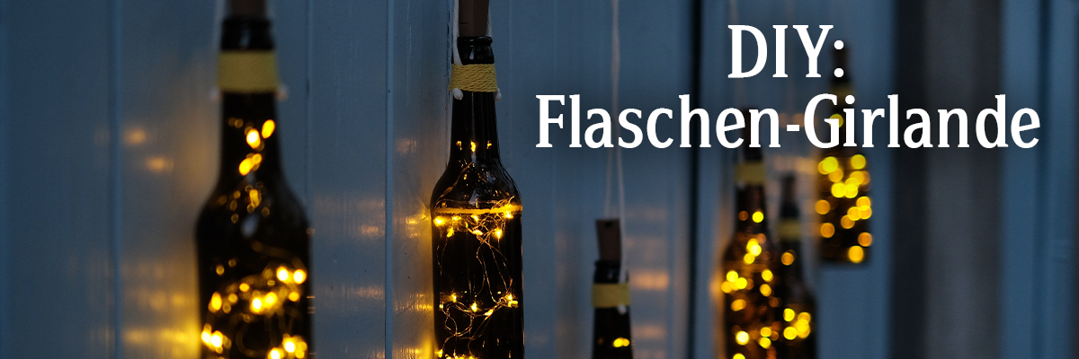 Zwei dekorierte Flaschen mit Lichtern hängen an einer Wand. Der Text 'DIY: Flaschen-Girlande' ist rechts im Bild sichtbar.