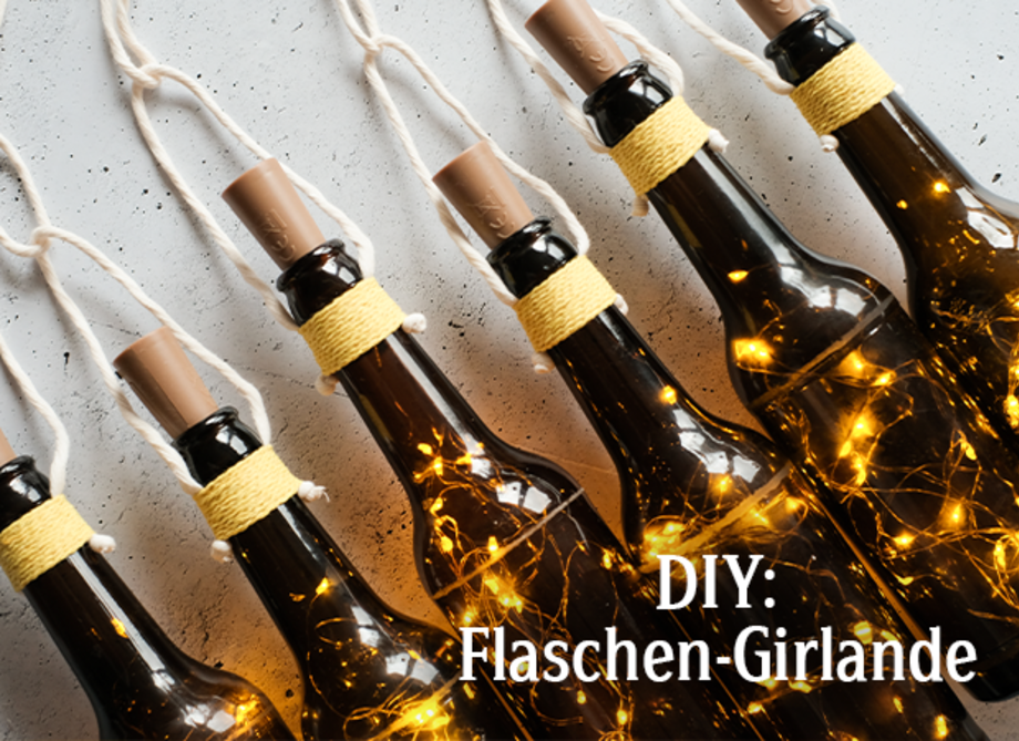 Sechs braune Glasflaschen mit Lichtern sind an einer Schnur aufgehängt. Darunter steht der Text 'DIY: Flaschen-Girlande'.