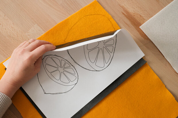 Aufgemalte Zitronen sind auf einem orangenen Filz.