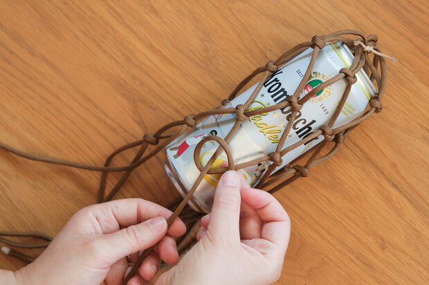 In das braune Seilnetz wird eine Krombacher Dose reingestellt.
