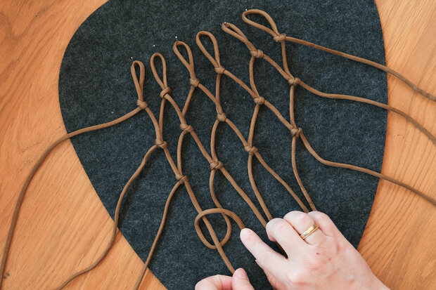 Aus einem braunen Seil wird ein Netz geknotet.