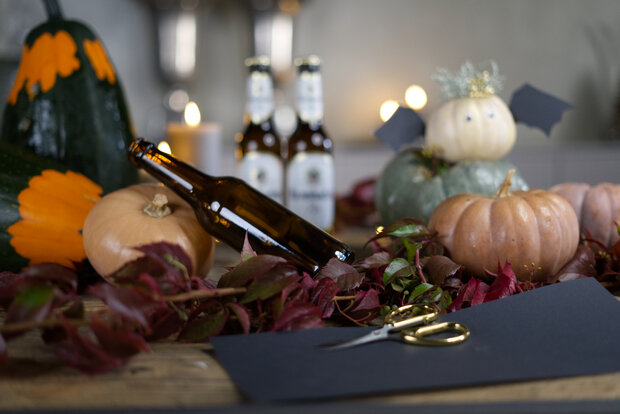 Liegende braune Flasche mit Herbstdekoration.