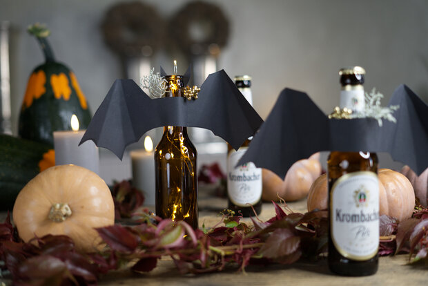 Ein herbstlich dekorierter Tisch mit Fledermausflaschen.
