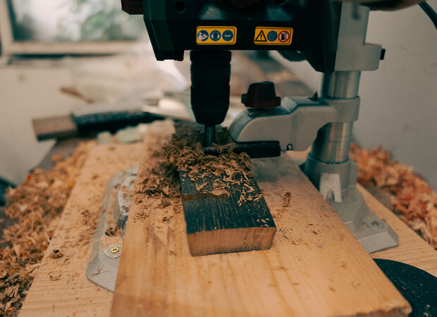 Holz wird mit einer Standbohrmaschine gebohrt.