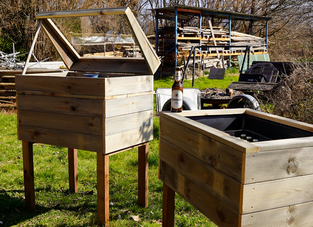 Zwei fertige Holzhochbeete stehen auf einer Wiese.