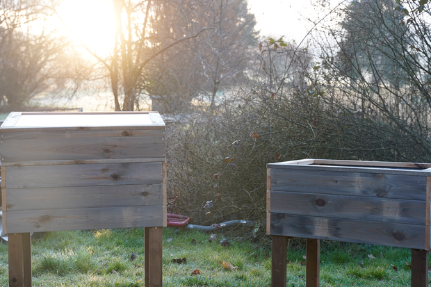 Zwei fertige Holzhochbeete stehen in der Abendsonne.