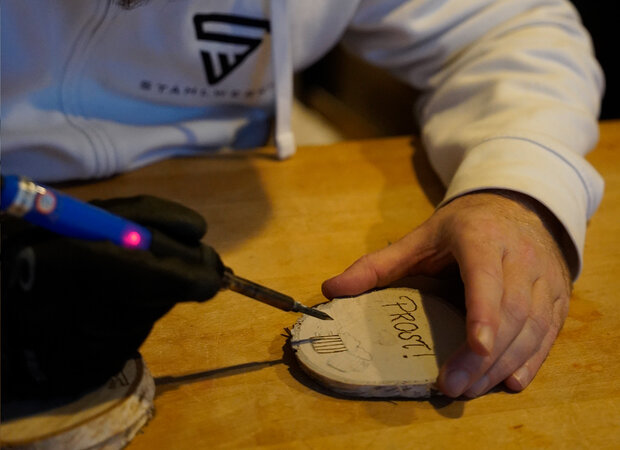 Eine Holzscheiben wird mit einem Lötkolben gelötet.