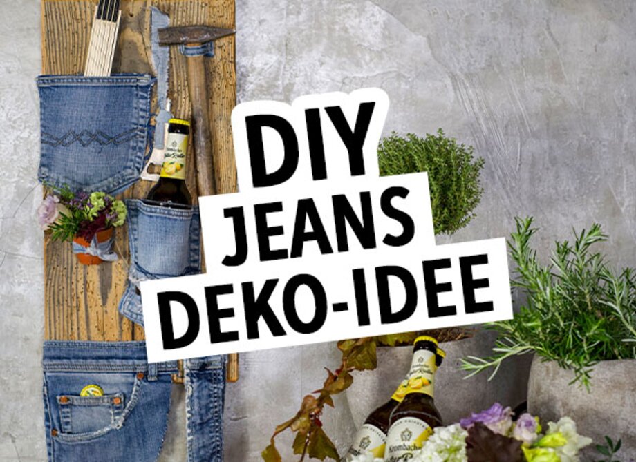 Ein Holzhintergrund zeigt eine kreative DIY-Deko-Idee mit Jeans. Auf der linken Seite hängen Jeans-Taschen mit Werkzeugen. In der Mitte steht der Text 'DIY JEANS DEKO-IDEE'. Unten sind zwei Flaschen mit Etiketten sichtbar.