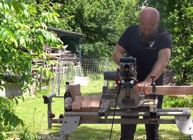 Balken wird mit Kreissäge in Holzkubbs gesägt.