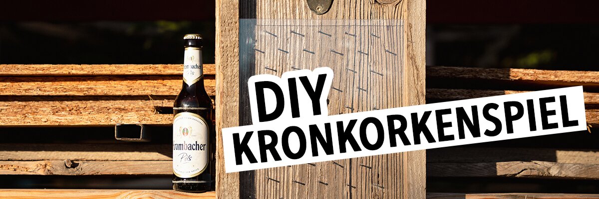 Ein Bierflasche von 'Kronbacher' steht neben einem Holzbrett mit Nägeln. Der Text 'DIY KRONKORENSPIEL' ist in fetter Schrift auf einem weißen Hintergrund.