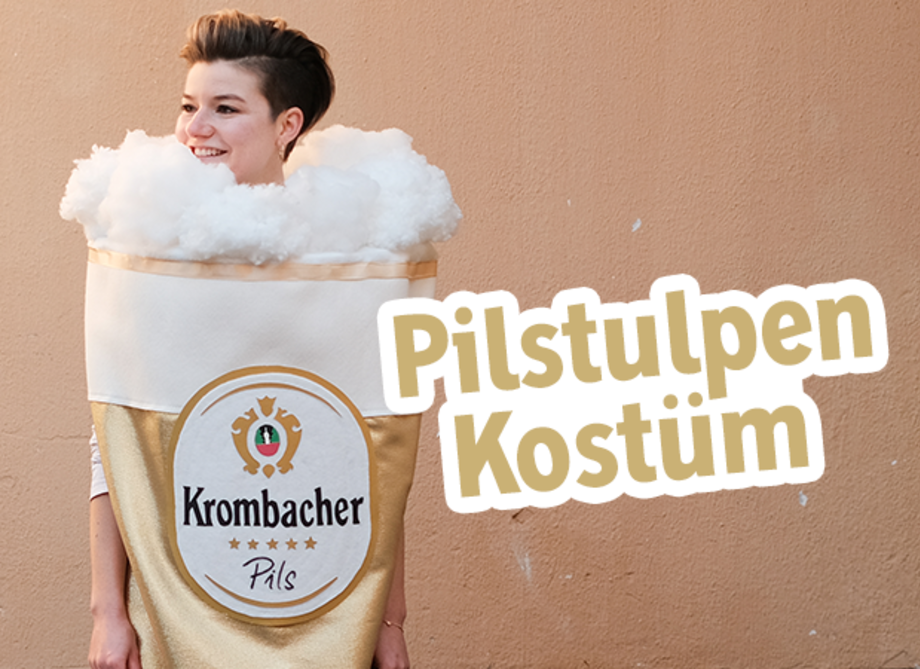 Eine Frau trägt ein Krombacher Pilskostüm mit dem Text: Krombacher Pilsstubenkostüm.