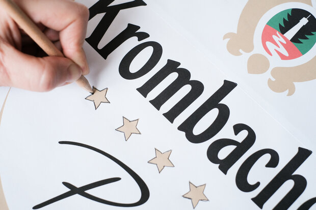 Krombacher Logo wird durchgepauscht mit Stift.