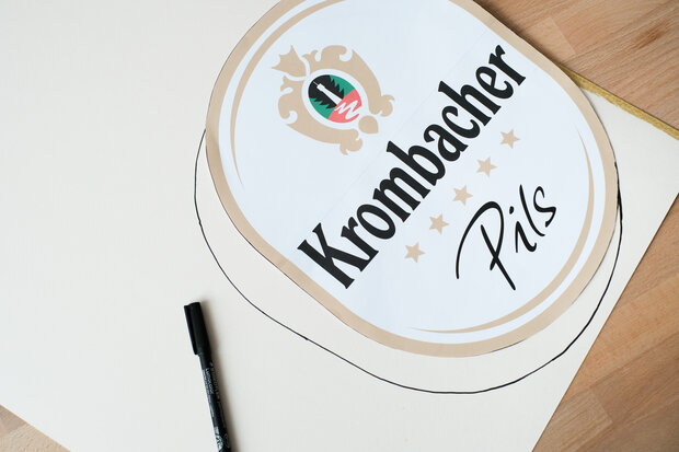 Ein Krombacher Etikett wird mit Stift umrandet.
