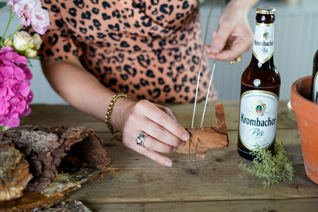 Durchbohrte Rindenstück wird mit Aludraht aufgefädelt.