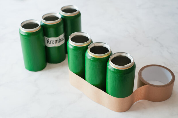 Sechs grüne Dosen werden zweireihig aneinander gebunden.