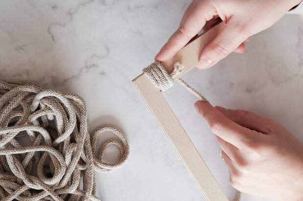 Obere Holzsteg wird mit einer Kordel umwickelt.