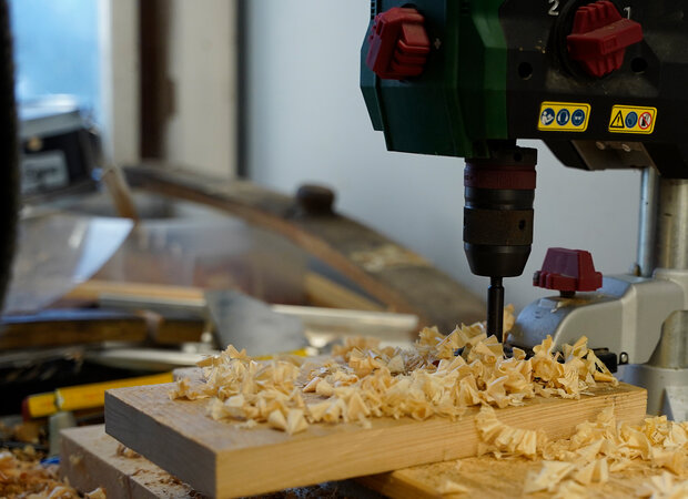 Ein Holzstück wird mit einem Standbohrer durchbohrt.