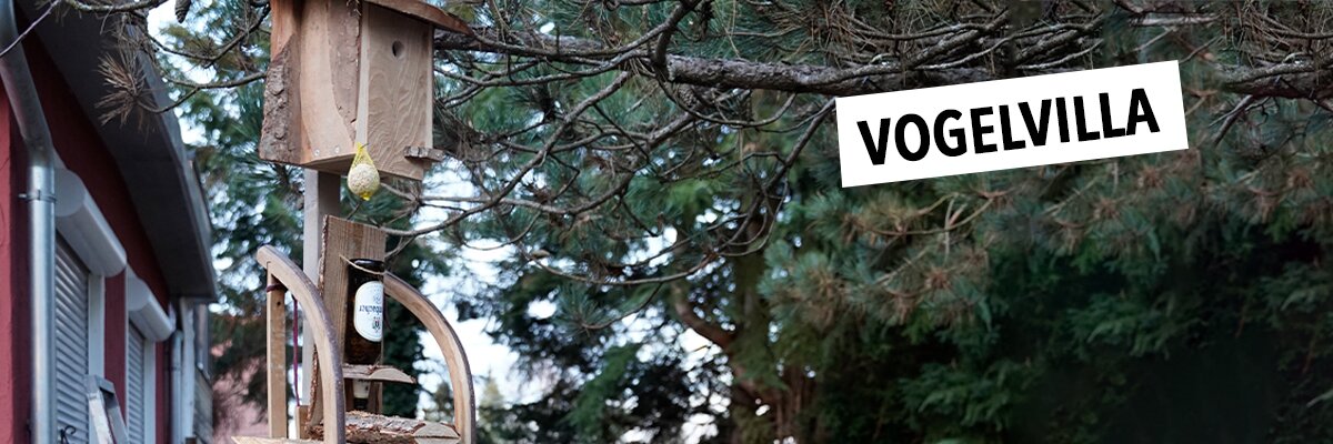 Ein Holzvogelhäuschen mit text: Vogelvilla.