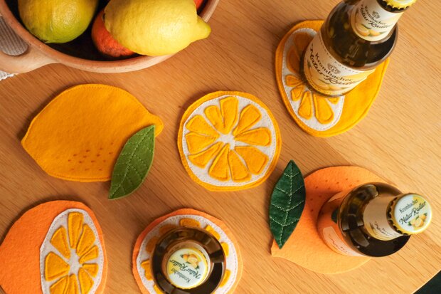 Fertige Zitronenuntersetzer mit Flaschen darauf.