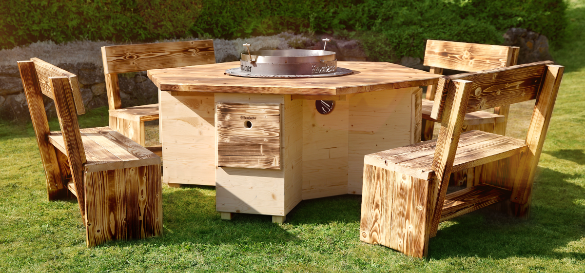 Runder Holztisch mit einem zentralen Grill, umgeben von vier rustikalen Holzsitzen. Der Tisch hat eine Holzoberfläche mit sichtbaren Maserungen.