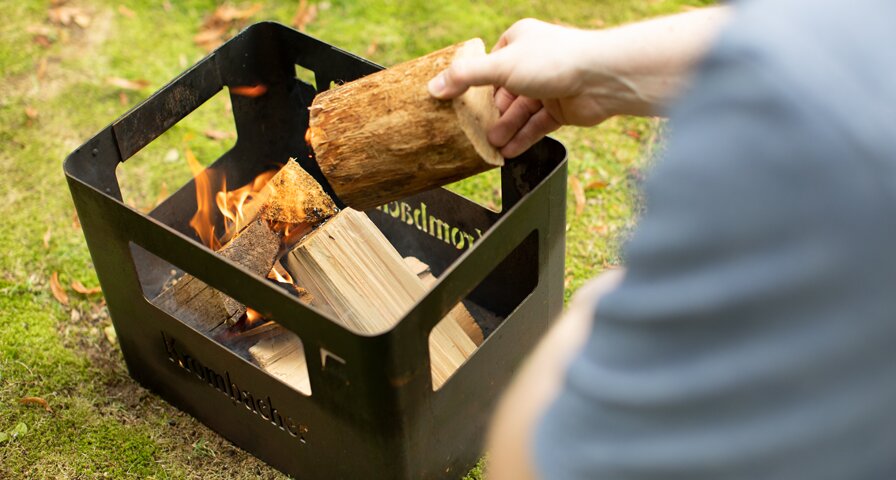 Holz wird in eine Feuerschale gelegt.