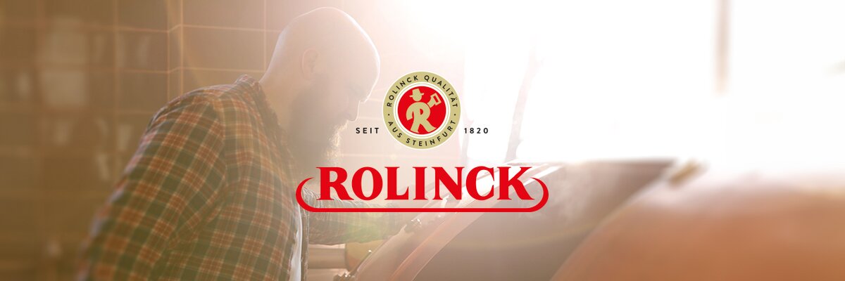 Ein Mann mit Glatze und kariertem Hemd beugt sich über einen großen Kessel. Darunter steht das Logo 'ROLINCK' in roter Schrift.