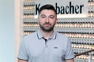 Mann mit schwarzen kurzen haaren und Bart, trägt ein hellgraues Poloshirt.