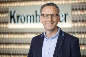 Mann mit kurzen, grauen Haaren trägt einen dunkelblauen Blazer und lächelt in die Kamera.