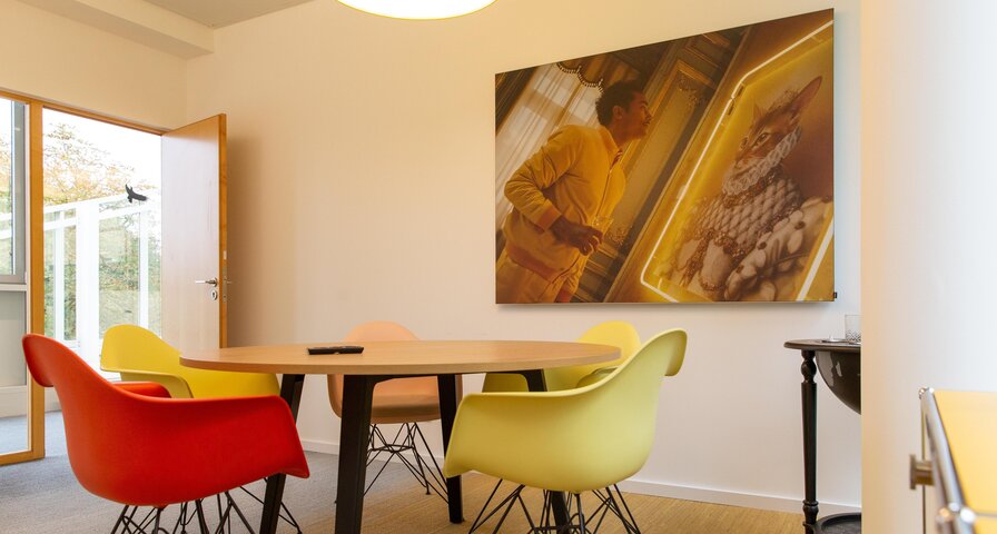 Ein runder Tisch mit vier Stühlen in rot, gelb und beige. 