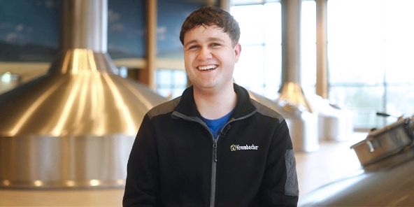 Mann mit kurzen braunen Haaren, trägt einen dunkelgrauen Pullover mit Krombacher Logo Aufdruck.